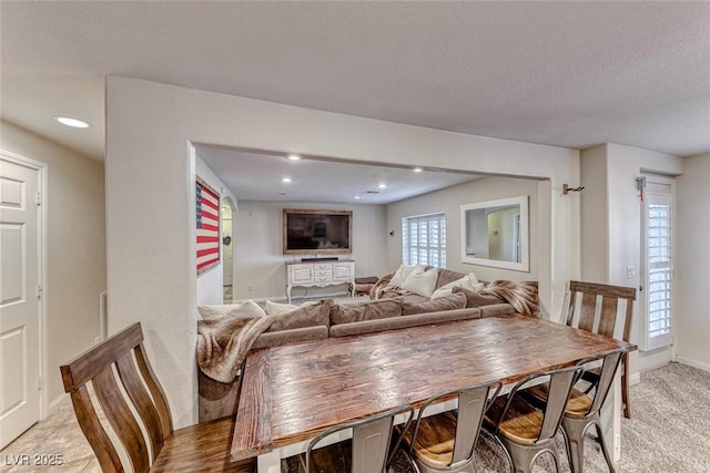 carpeted dining space featuring a textured ceiling