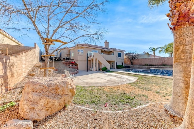 back of property featuring a fenced in pool, a balcony, and a patio area