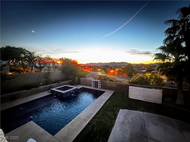 pool at dusk featuring a mountain view, a fire pit, and a patio area