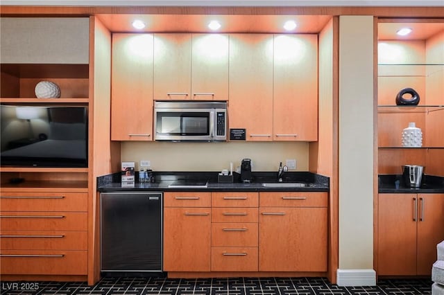 kitchen featuring sink, cooktop, fridge, and dark stone countertops