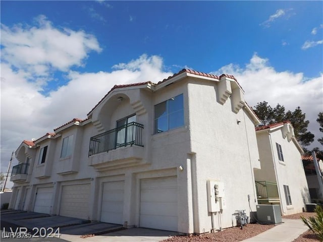 view of side of property featuring a balcony, a garage, and central air condition unit