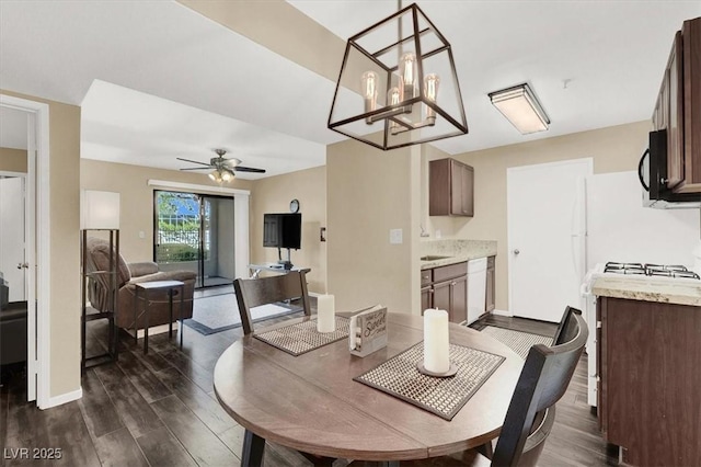 dining area with ceiling fan with notable chandelier and dark hardwood / wood-style flooring