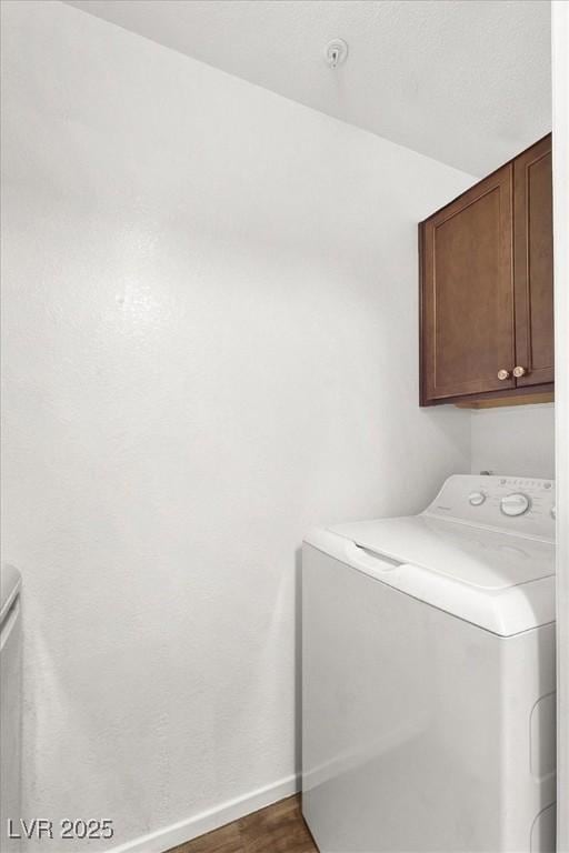 laundry room featuring dark hardwood / wood-style flooring, washer / clothes dryer, and cabinets