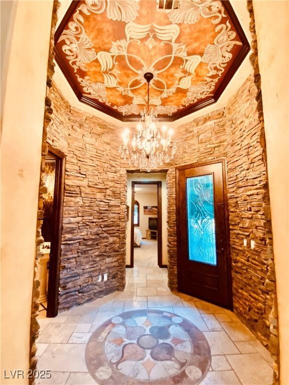 foyer entrance featuring an inviting chandelier, ornamental molding, and a raised ceiling