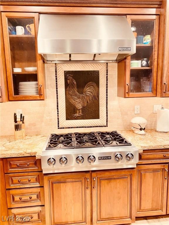 kitchen featuring light stone counters, stainless steel gas cooktop, extractor fan, and decorative backsplash