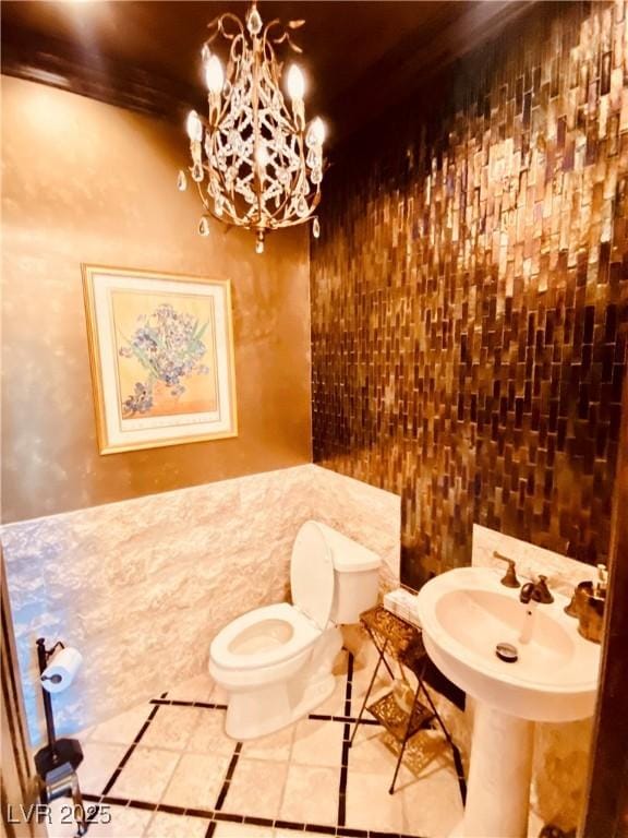 bathroom featuring an inviting chandelier, toilet, and tile patterned flooring