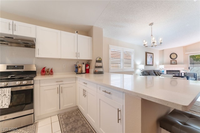 kitchen featuring white cabinets, a healthy amount of sunlight, kitchen peninsula, and gas range