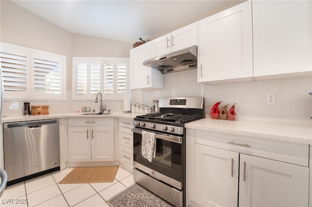 kitchen with white cabinetry, light tile patterned floors, sink, stainless steel appliances, and lofted ceiling