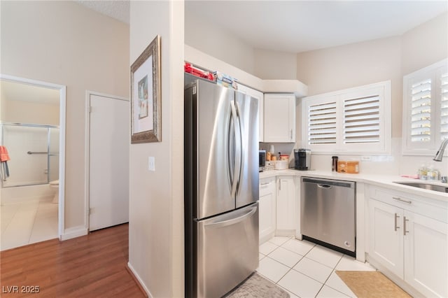 kitchen with white cabinets, stainless steel appliances, light tile patterned floors, and sink