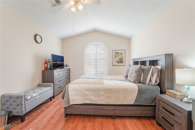 bedroom featuring hardwood / wood-style flooring, a textured ceiling, vaulted ceiling, and ceiling fan