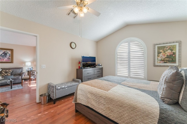 bedroom with lofted ceiling, wood-type flooring, a textured ceiling, and ceiling fan