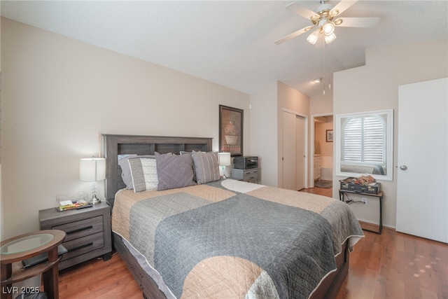 bedroom featuring ceiling fan, hardwood / wood-style flooring, ensuite bathroom, and lofted ceiling