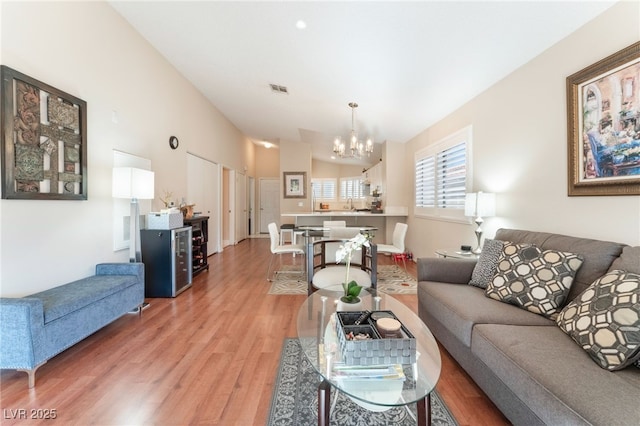 living room with hardwood / wood-style floors, a chandelier, and vaulted ceiling