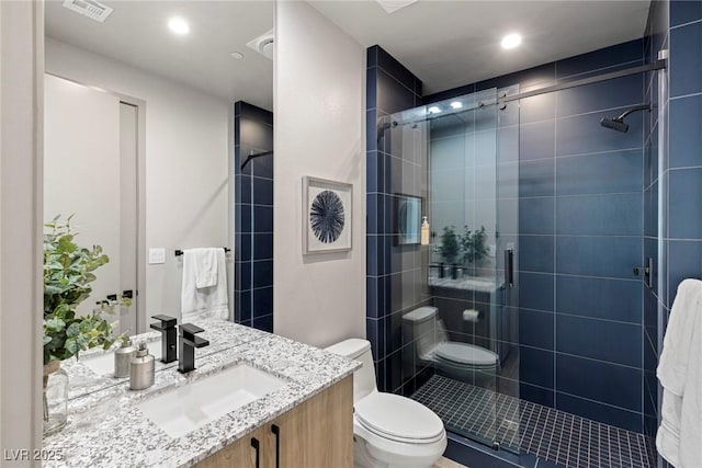 bathroom with toilet, a stall shower, visible vents, and vanity