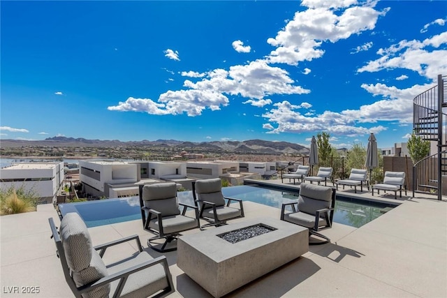 view of patio with a fire pit, stairway, a mountain view, and a fenced in pool