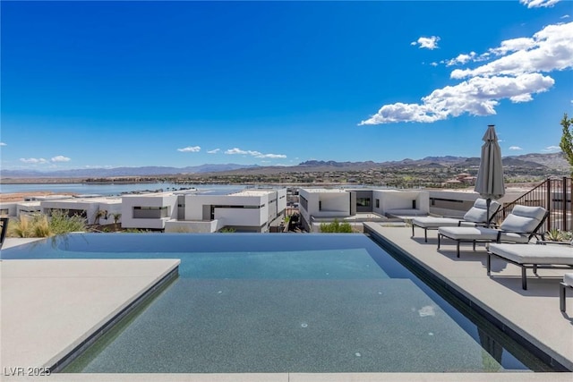 view of pool with a patio area, an infinity pool, and a mountain view