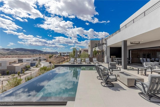 view of swimming pool with a patio, a mountain view, a fire pit, stairway, and a fenced in pool