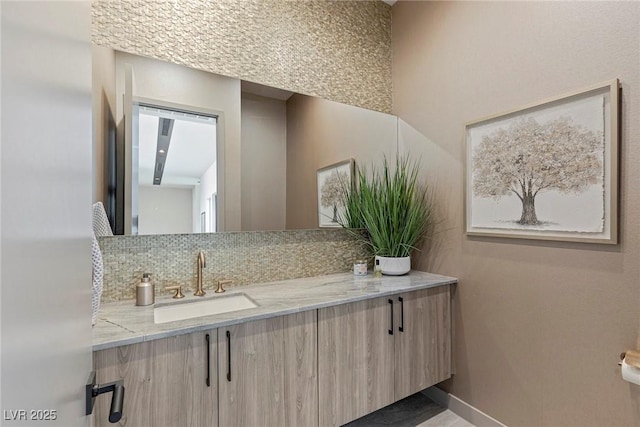 bathroom featuring tasteful backsplash, vanity, and baseboards