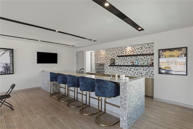 bar with baseboards, indoor wet bar, and wood finish floors