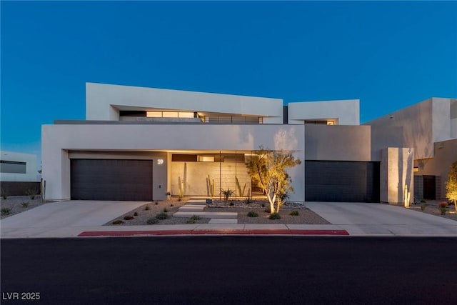 modern home featuring a garage, concrete driveway, and stucco siding