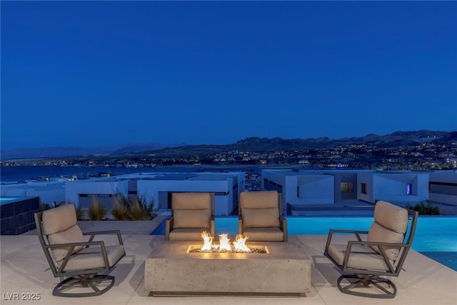 view of patio featuring a fenced in pool, an outdoor fire pit, and a mountain view