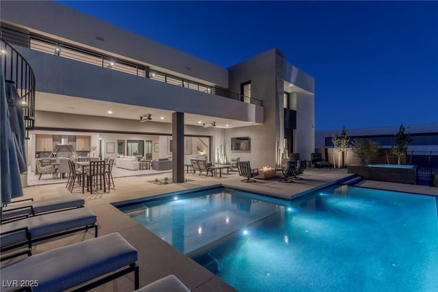 pool at night with an in ground hot tub, fence, a fenced in pool, and a patio