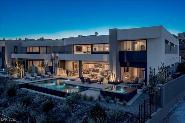 back of house featuring an infinity pool, stucco siding, a patio area, an in ground hot tub, and stairs