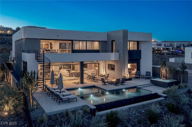 rear view of house with an outdoor fire pit, a patio, stairs, a pool with connected hot tub, and stucco siding