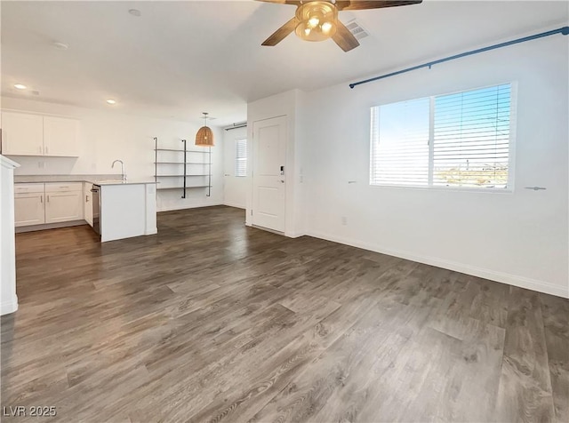 unfurnished living room with sink, dark wood-type flooring, and ceiling fan