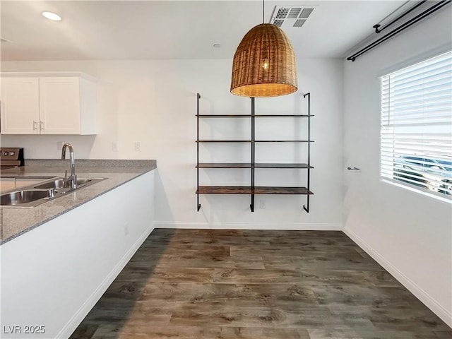 kitchen featuring pendant lighting, white cabinets, dark hardwood / wood-style flooring, sink, and light stone counters