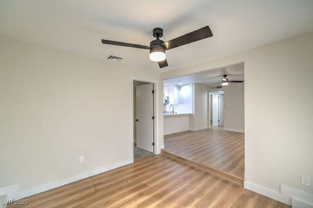 spare room featuring sink, ceiling fan, and wood-type flooring