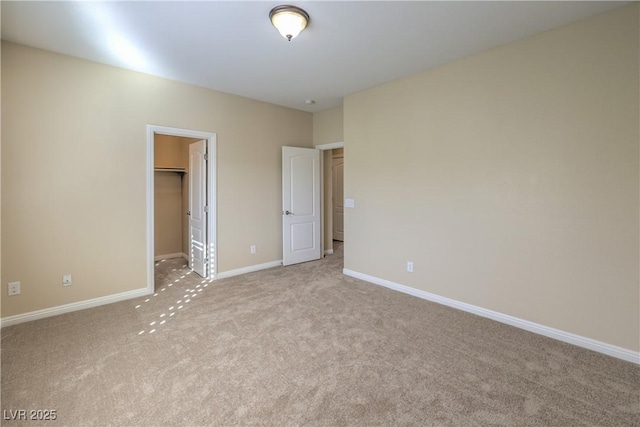 unfurnished bedroom featuring a spacious closet, a closet, and light carpet