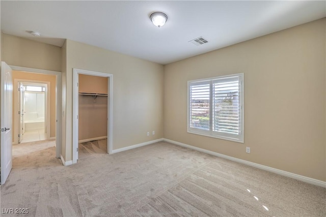 unfurnished bedroom featuring light carpet, a closet, and a walk in closet