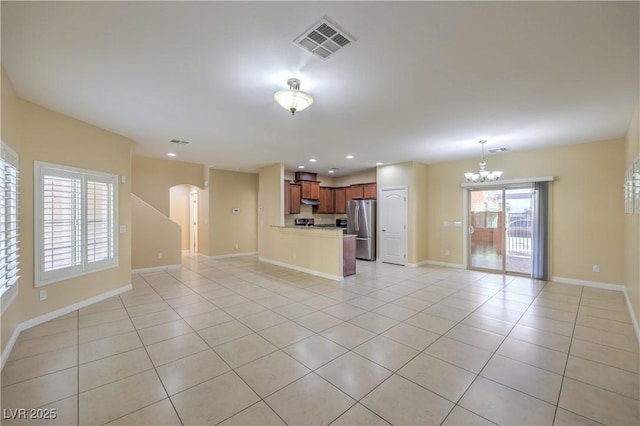 unfurnished living room with a chandelier and light tile patterned floors