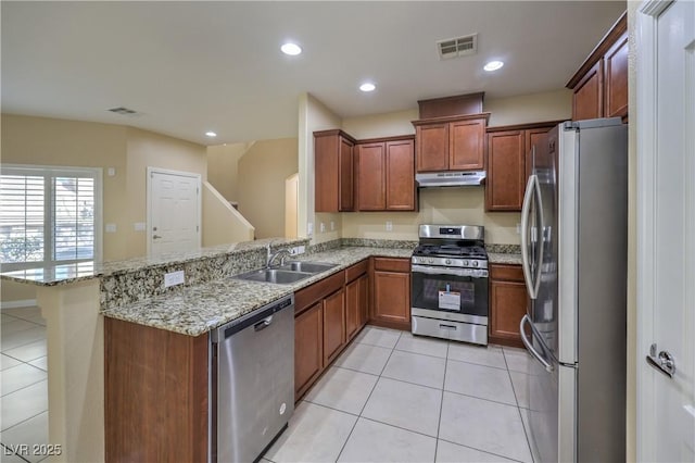 kitchen with light stone countertops, light tile patterned floors, sink, kitchen peninsula, and stainless steel appliances