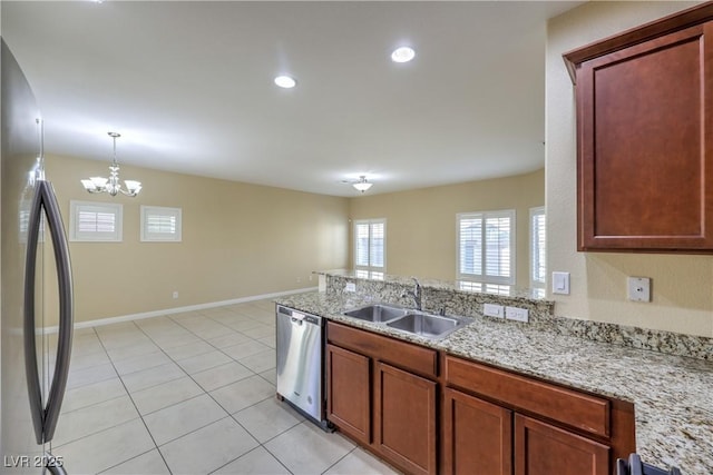 kitchen with pendant lighting, appliances with stainless steel finishes, sink, light tile patterned floors, and light stone counters