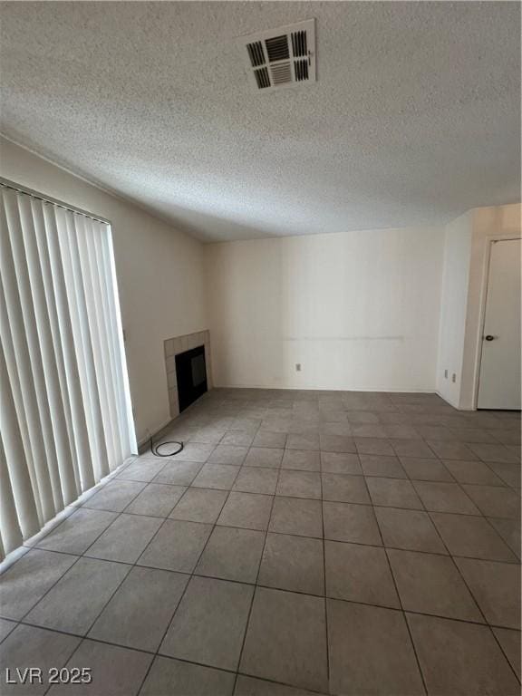 unfurnished living room with a textured ceiling, a tile fireplace, and tile patterned flooring