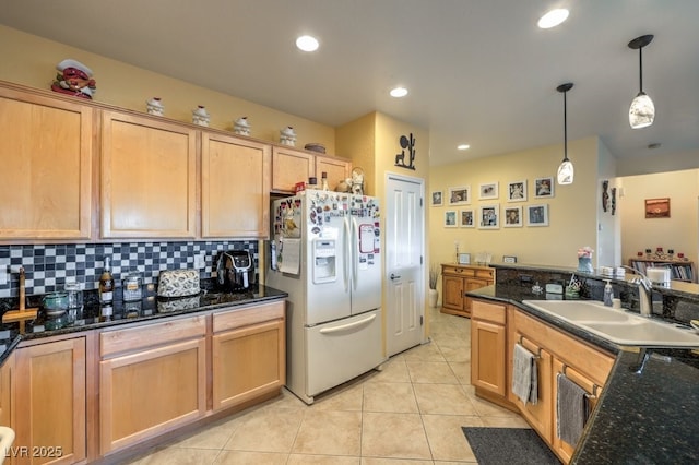 kitchen featuring light brown cabinetry, white refrigerator with ice dispenser, sink, decorative light fixtures, and tasteful backsplash