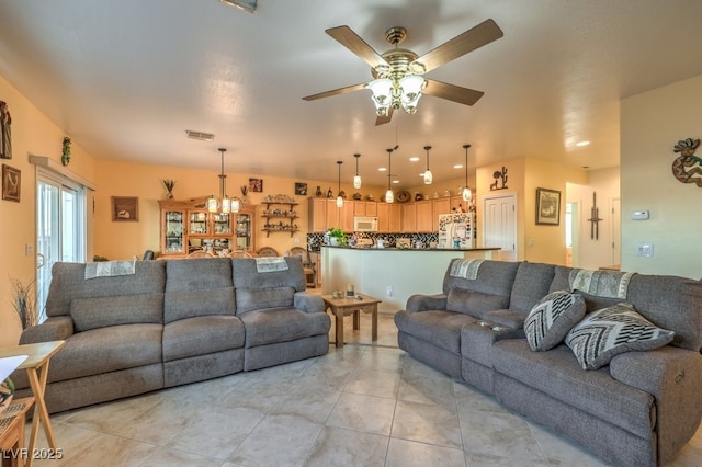 tiled living room featuring ceiling fan with notable chandelier