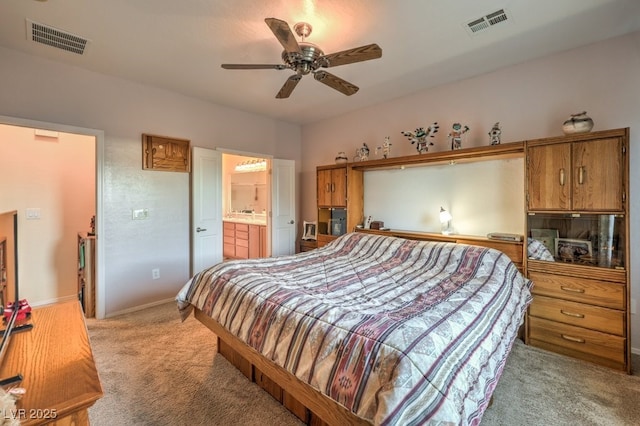 bedroom with ceiling fan, ensuite bathroom, and light carpet