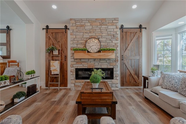 living room with light wood-type flooring, vaulted ceiling, and a barn door