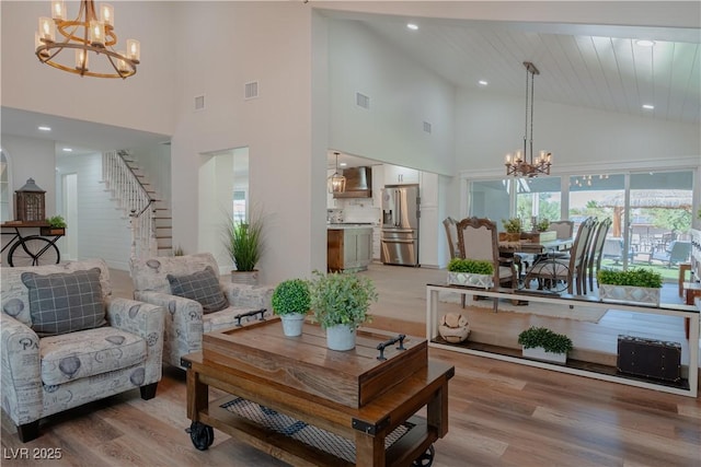 living room with a notable chandelier, a towering ceiling, and light hardwood / wood-style floors