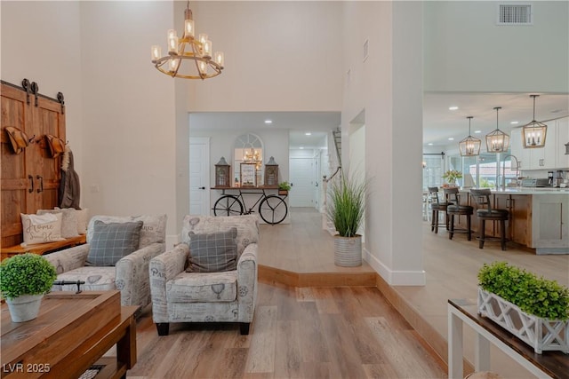 living area featuring light hardwood / wood-style flooring, a notable chandelier, and a barn door