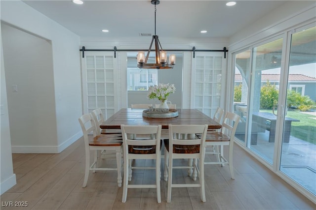 dining area with light hardwood / wood-style floors and a barn door