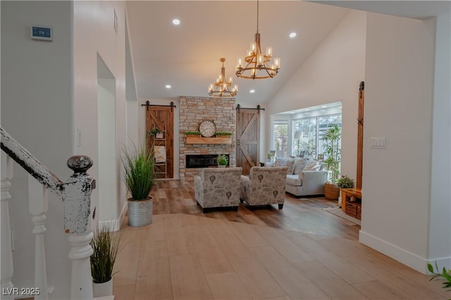 living room with light hardwood / wood-style floors, high vaulted ceiling, a barn door, and an inviting chandelier