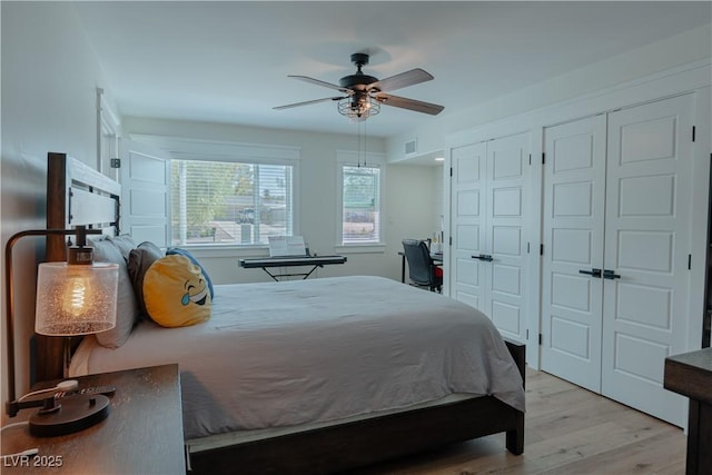 bedroom featuring multiple closets, light hardwood / wood-style floors, and ceiling fan