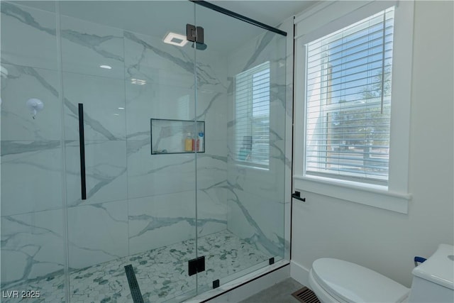 bathroom featuring a shower with shower door and toilet