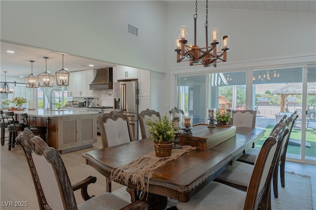 dining area with high vaulted ceiling, sink, and a chandelier