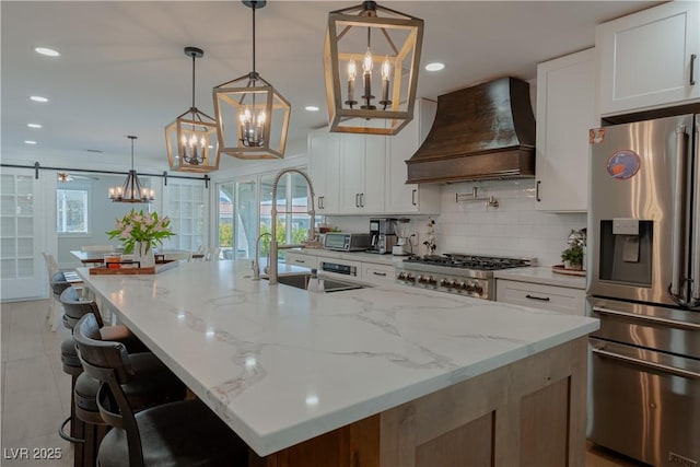 kitchen with a spacious island, white cabinetry, hanging light fixtures, stainless steel fridge with ice dispenser, and custom range hood