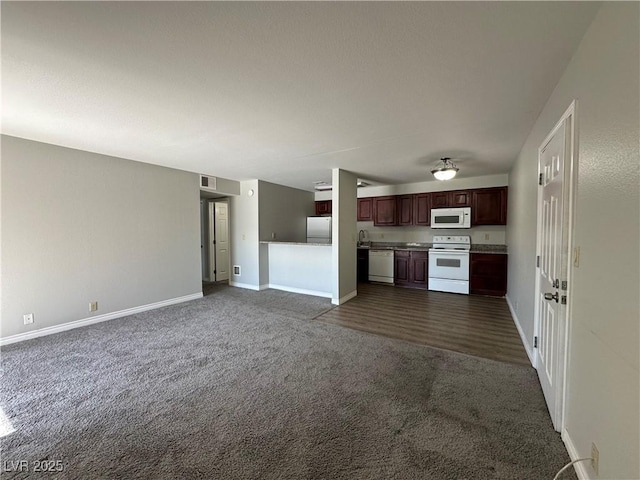 kitchen with sink, white appliances, and dark colored carpet